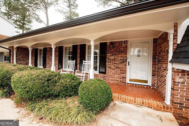 property entrance with brick siding and a porch