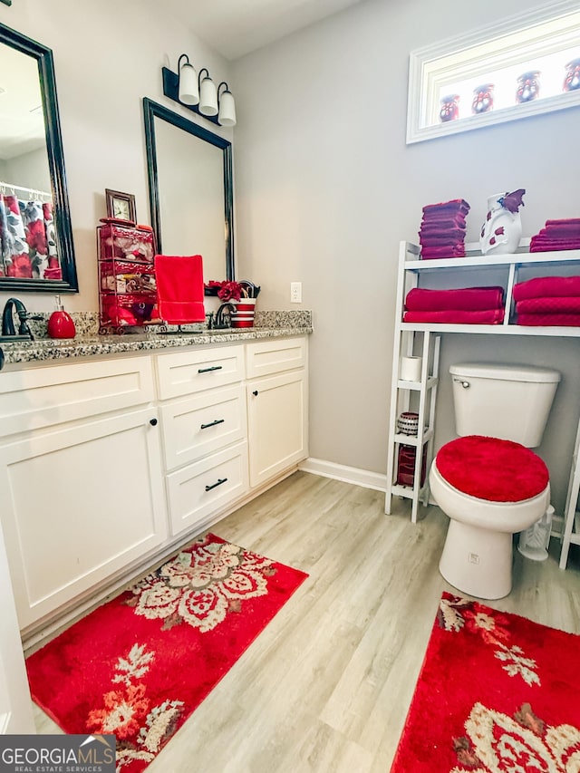 full bath with toilet, vanity, baseboards, and wood finished floors