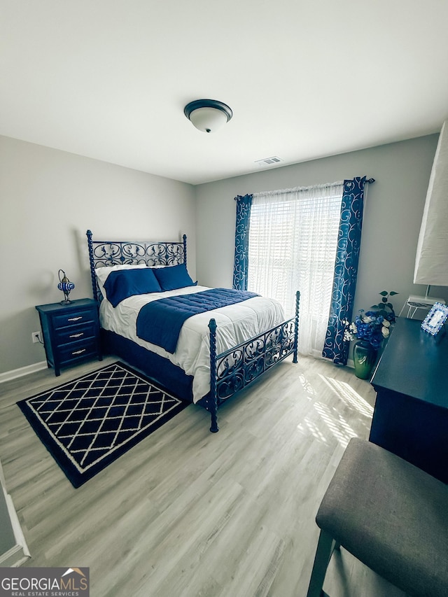 bedroom with visible vents, baseboards, and wood finished floors