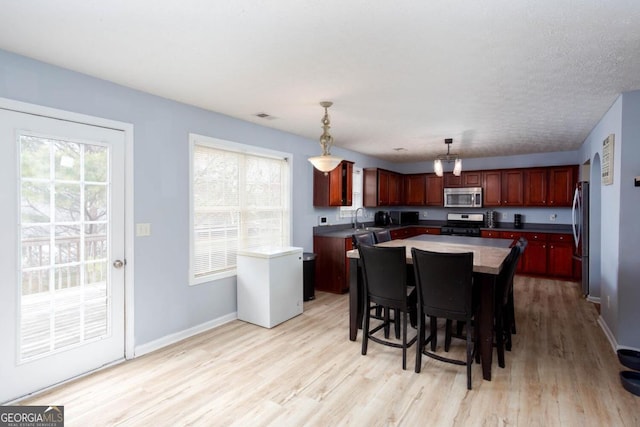 kitchen with a sink, stainless steel appliances, a center island, and light wood finished floors