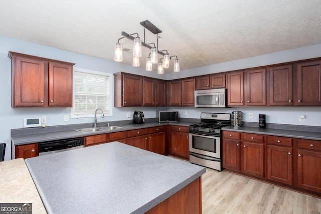 kitchen featuring pendant lighting, light wood-style flooring, a sink, a textured ceiling, and stainless steel appliances