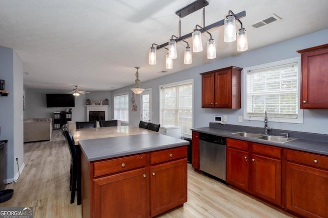 kitchen with visible vents, open floor plan, dishwasher, a fireplace, and a sink