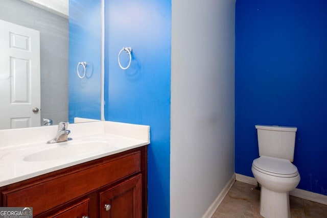 bathroom featuring vanity, toilet, baseboards, and tile patterned flooring