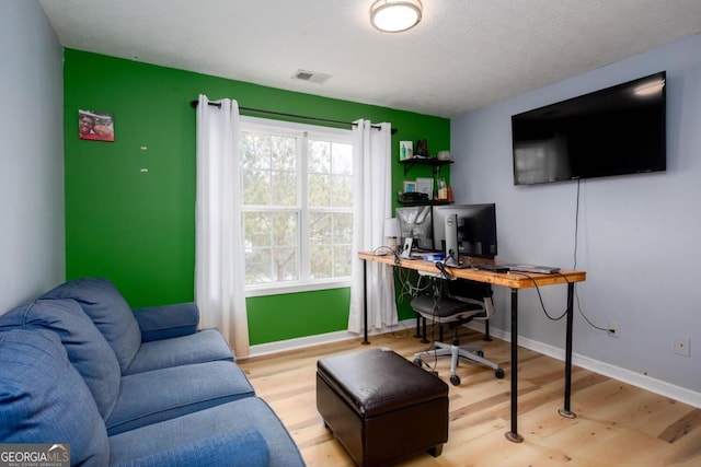 office featuring a textured ceiling, wood finished floors, visible vents, and baseboards