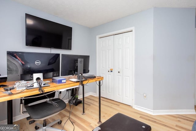 office featuring a textured ceiling, baseboards, and wood finished floors