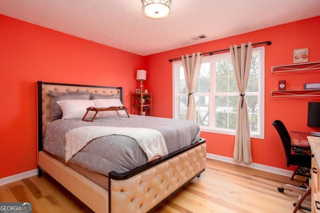 bedroom featuring visible vents, baseboards, and wood finished floors