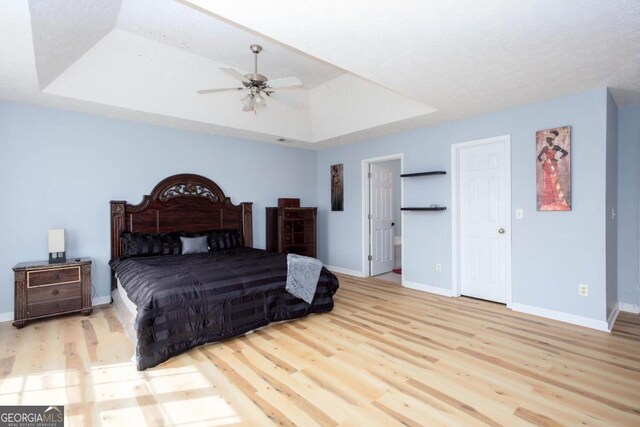 bedroom featuring baseboards, a raised ceiling, and wood finished floors