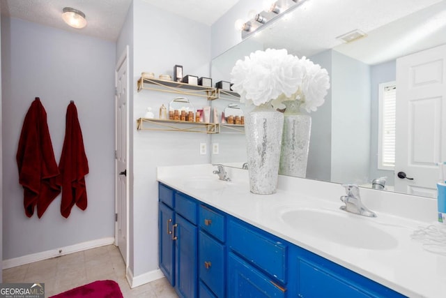 bathroom with double vanity, visible vents, baseboards, and a sink