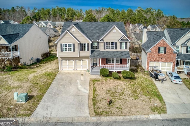 view of front of house with a porch, an attached garage, a residential view, and driveway