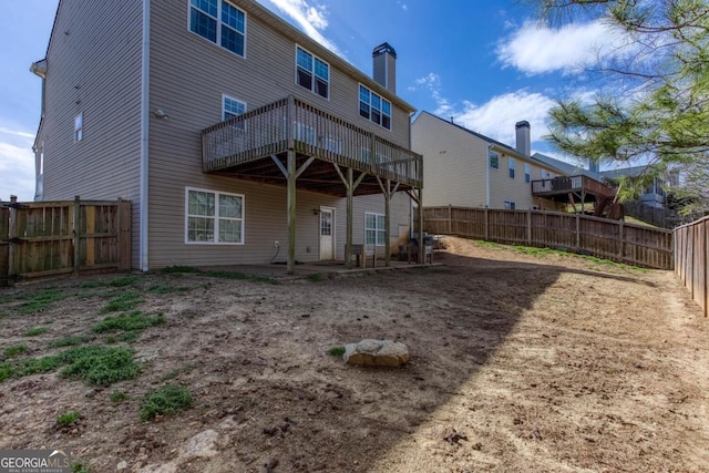 rear view of property featuring a deck, a fenced backyard, and a patio area