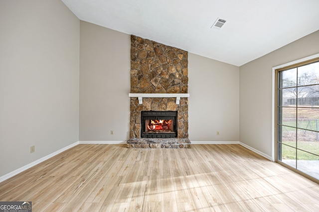 unfurnished living room featuring visible vents, baseboards, vaulted ceiling, a fireplace, and wood finished floors