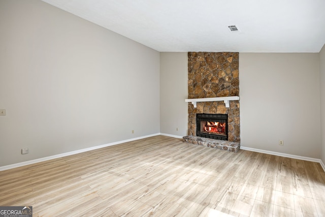 unfurnished living room featuring a stone fireplace, visible vents, baseboards, and light wood-type flooring