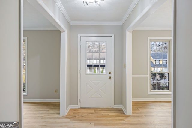 foyer featuring visible vents, baseboards, crown molding, and light wood finished floors