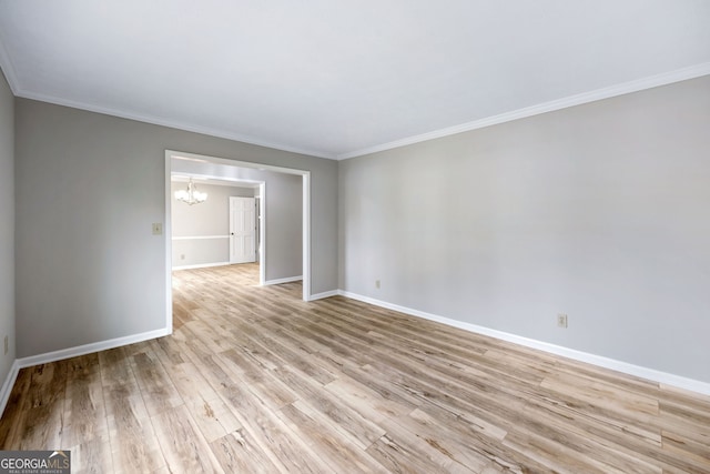 spare room featuring a chandelier, baseboards, light wood-style floors, and ornamental molding