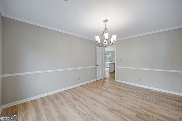 unfurnished room featuring a notable chandelier, light wood-style flooring, crown molding, and baseboards