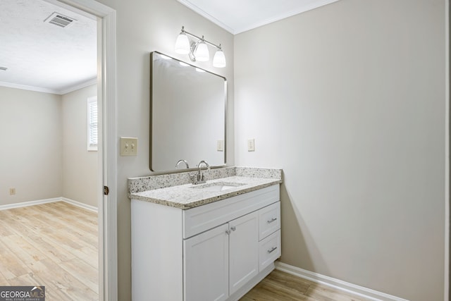 bathroom featuring crown molding, wood finished floors, visible vents, and baseboards