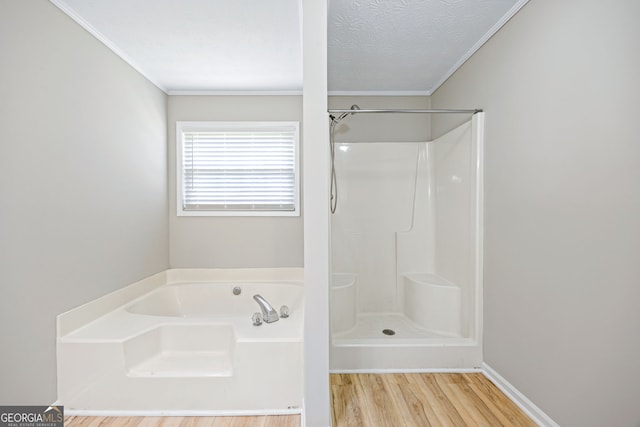 bathroom featuring wood finished floors, ornamental molding, a shower, a textured ceiling, and a bath