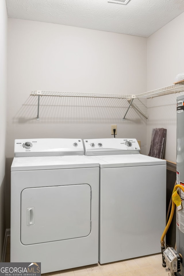 washroom with a textured ceiling, laundry area, and washing machine and clothes dryer