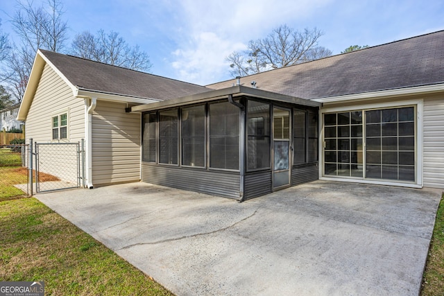 back of property with a patio area, a sunroom, fence, and a gate