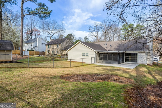 back of property featuring an outbuilding, a lawn, fence, a storage shed, and a sunroom