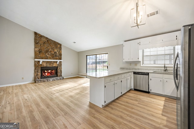 kitchen with a sink, open floor plan, stainless steel appliances, a peninsula, and lofted ceiling