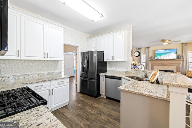 kitchen featuring a sink, dishwasher, dark wood finished floors, a peninsula, and refrigerator with ice dispenser