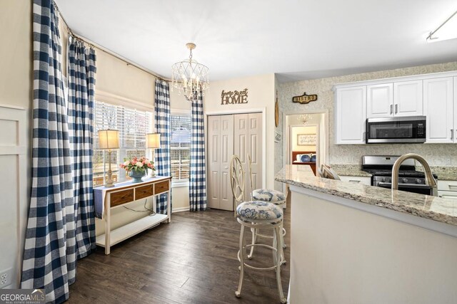 49 Inverness Ct, Hiram, GA 30141 - kitchen with stainless steel appliances, dark wood-style flooring, a chandelier, white cabinets, and light stone countertops