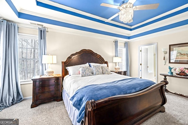 bedroom featuring carpet flooring, a tray ceiling, visible vents, and multiple windows