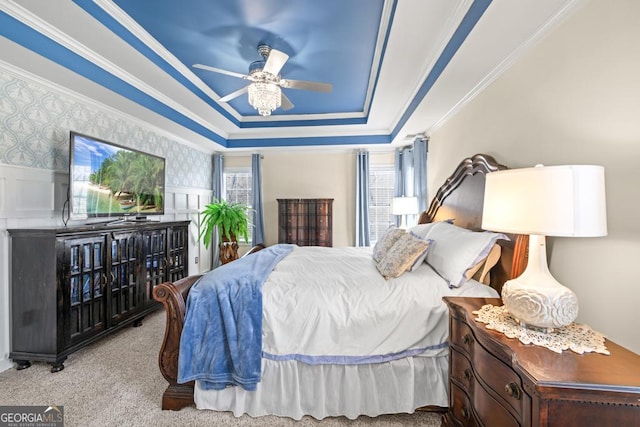 carpeted bedroom with ornamental molding, a raised ceiling, and a ceiling fan