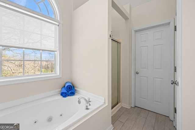 full bath with a jetted tub, plenty of natural light, and a stall shower