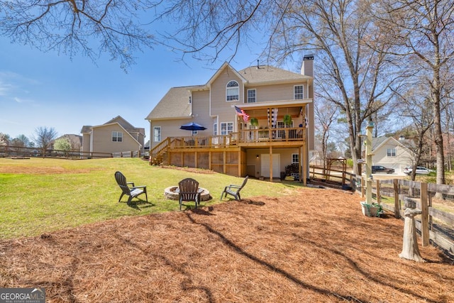 back of house featuring fence, a deck, a chimney, a lawn, and an outdoor fire pit