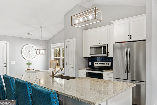 kitchen featuring visible vents, a sink, stainless steel appliances, vaulted ceiling, and white cabinets