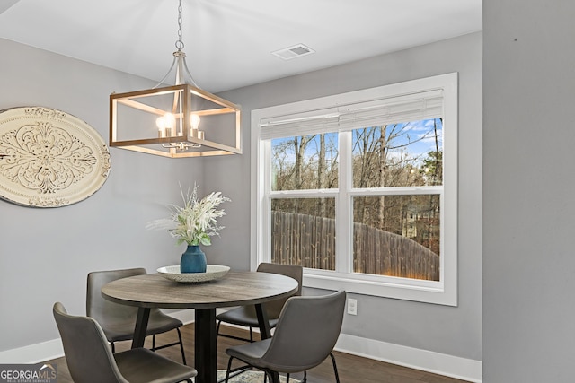 dining area with dark wood finished floors, an inviting chandelier, baseboards, and visible vents