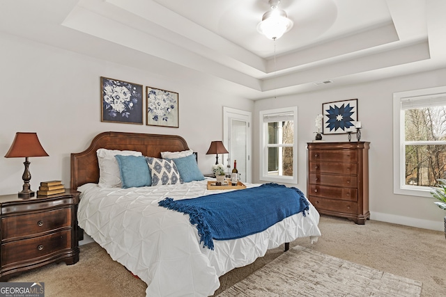 carpeted bedroom featuring a raised ceiling, baseboards, and visible vents