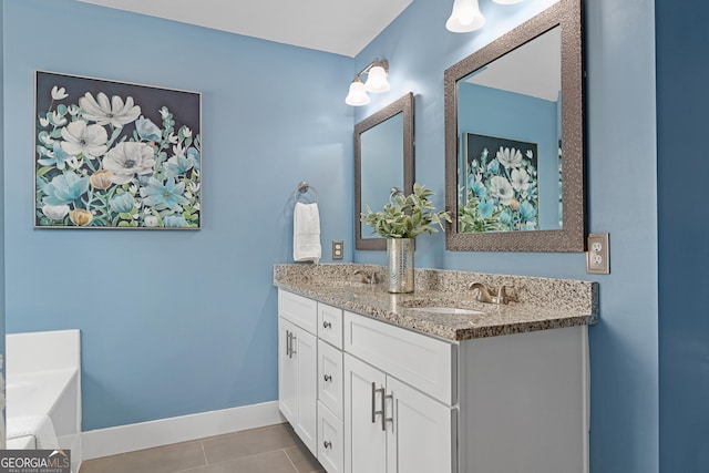 bathroom with baseboards, a garden tub, double vanity, tile patterned floors, and a sink