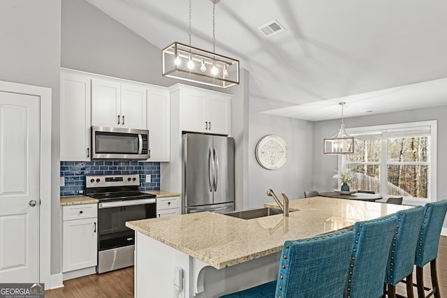 kitchen featuring visible vents, a breakfast bar, appliances with stainless steel finishes, an inviting chandelier, and decorative backsplash