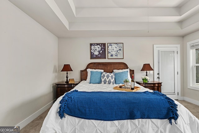 carpeted bedroom with a tray ceiling and baseboards