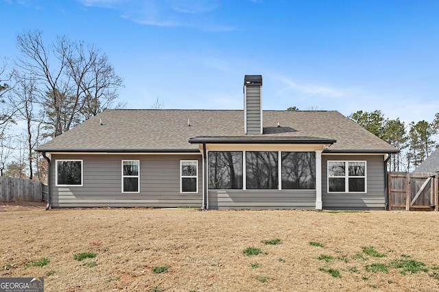 back of house with a chimney, roof with shingles, and fence