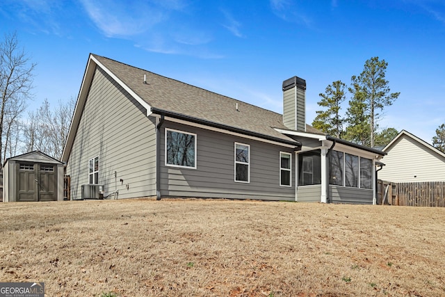 back of property with fence, a chimney, a storage shed, an outdoor structure, and a sunroom