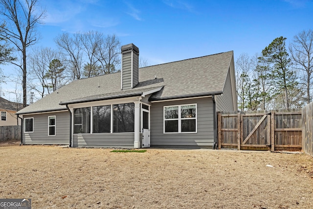 back of property featuring a gate, a shingled roof, fence, a sunroom, and a chimney