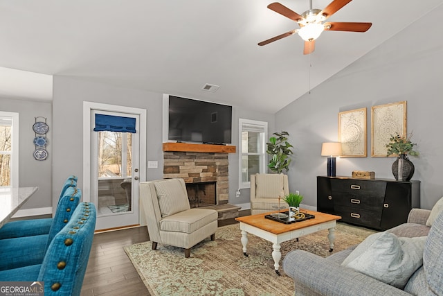 living room with visible vents, ceiling fan, vaulted ceiling, a fireplace, and wood finished floors