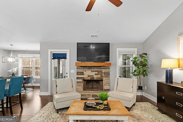 living room featuring a ceiling fan, baseboards, wood finished floors, visible vents, and a fireplace