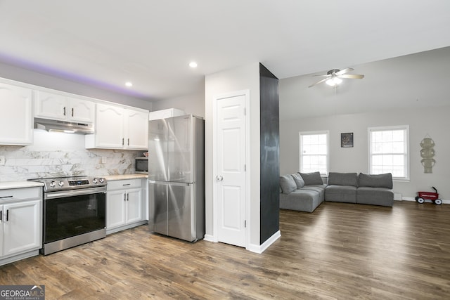 kitchen with under cabinet range hood, stainless steel appliances, backsplash, and white cabinetry