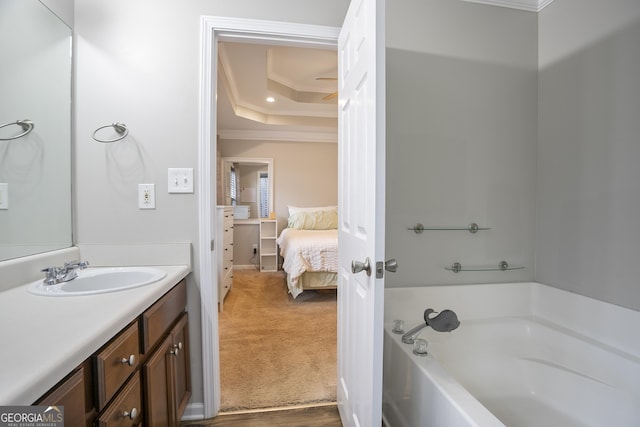 ensuite bathroom featuring crown molding, a garden tub, ensuite bathroom, vanity, and a raised ceiling