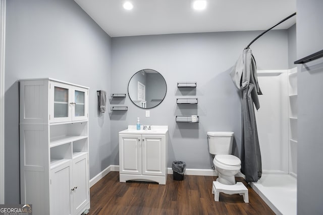 full bath featuring a shower with curtain, toilet, wood finished floors, baseboards, and vanity