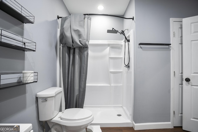 full bathroom featuring baseboards, toilet, and a stall shower