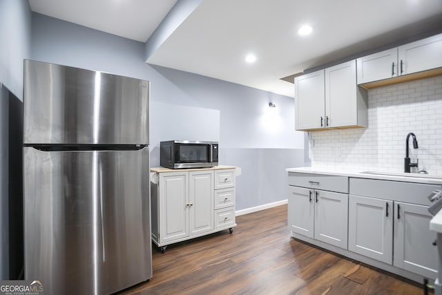 kitchen featuring dark wood finished floors, a sink, light countertops, appliances with stainless steel finishes, and tasteful backsplash