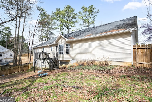 rear view of house with stairway, fence, and a wooden deck