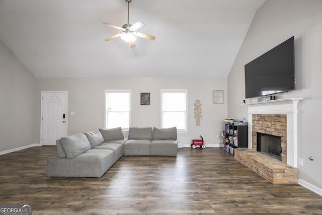 living room featuring dark wood finished floors, a stone fireplace, baseboards, and ceiling fan