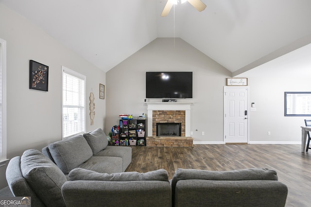 living room featuring high vaulted ceiling, dark wood-style floors, a stone fireplace, baseboards, and ceiling fan